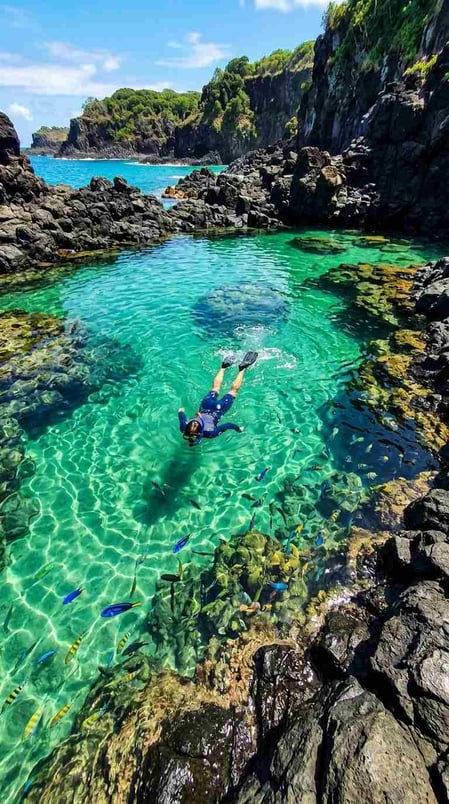 A snorkeler floats in an emerald tide pool in this aspirational Baia dos Porcos guide image.
