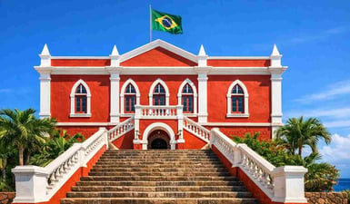 The bright red colonial façade of the São Miguel Palace in Fernando de Noronha, Brazil, under a clear blue sky with the Brazilian flag flying.
