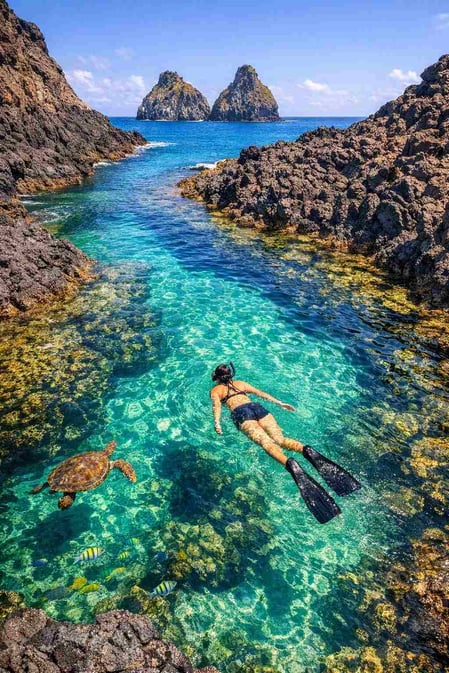 In questa suggestiva immagine della guida dedicata a Baia dos Porcos, un appassionato di snorkeling galleggia in una pozza di marea color smeraldo.