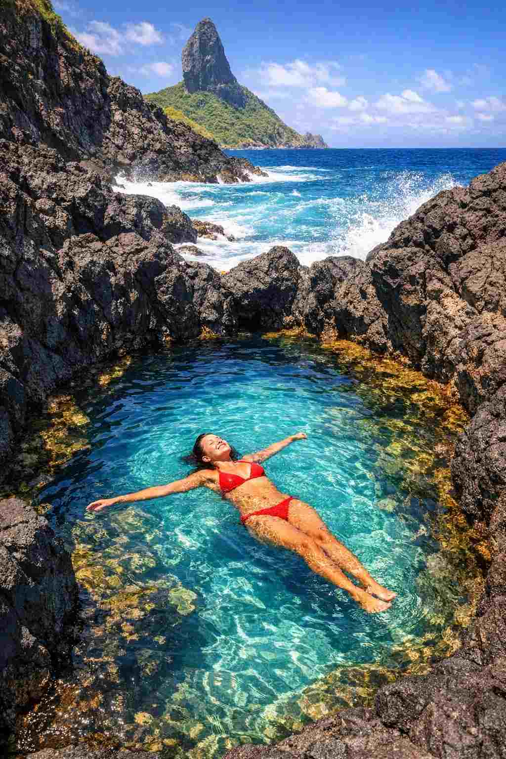 Uma pessoa nadando na piscina natural de águas azul-turquesa da Praia do Cachorro, um dos destaques do nosso guia de viagem de Fernando de Noronha.
